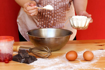 closeup arabic woman is cooking a cake, making or cooking background frame. Ingredients, kitchen items for baking cakes. Kitchen utensils, flour, eggs, candied cherry, chocolate, flour. Text space.