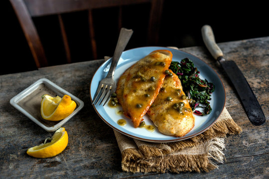 Close up of chicken piccata with chard served on plate