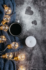  Cup of coffee , candle, notebook, pen and warm woolen sweater , decorated with led lights on gray table.Winter  concept. Flat lay, top view. Valentines day.