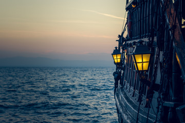 oud houten vintage piratenschip op zeewateroppervlak in zonsondergang avond romantische tijd met geel licht van soft focus lantaarn in overboord ruimte