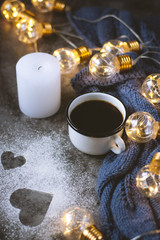 Fototapeta na wymiar Cup of coffee , candle, notebook, pen and warm woolen sweater , decorated with led lights on gray table.Winter concept. Flat lay, top view. Valentines day.