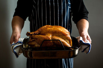 Midsection of man holding baked  turkey in baking tray