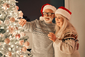 The happy old couple decorating the christmas tree