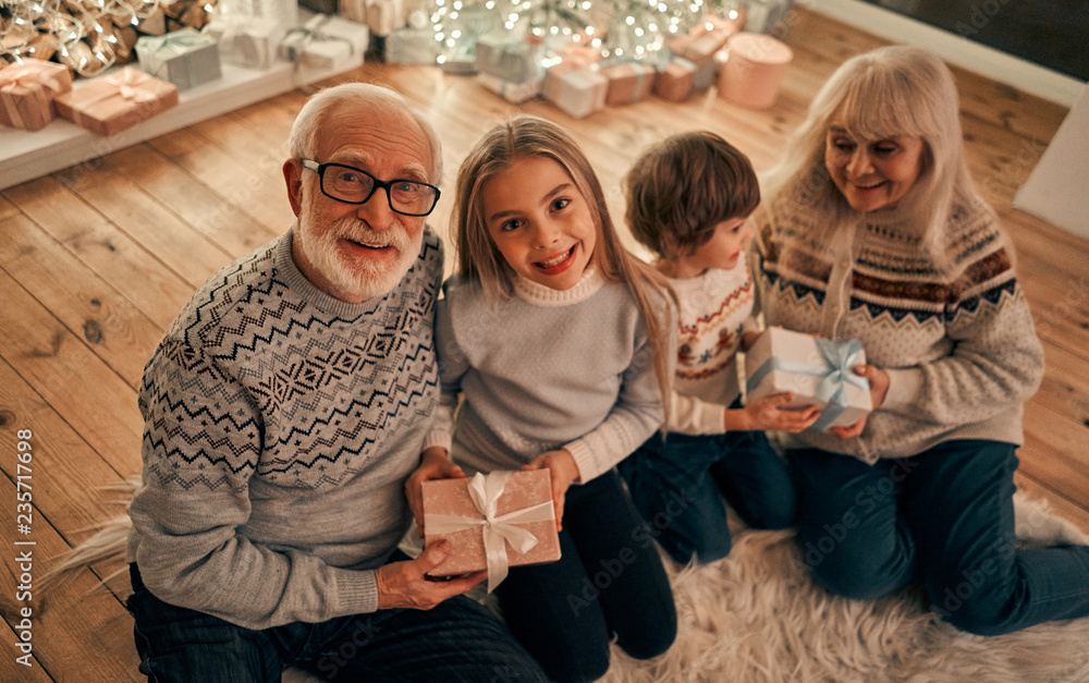 Wall mural The happy grandparents giving gifts to children