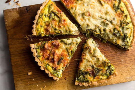 Close Up Of Roasted Asparagus And Scallion Quiche Slices On Cutting Board