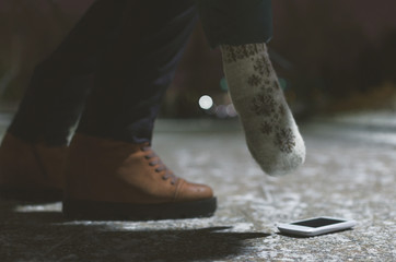 Find a mobile phone concept. Lost mobile phone on the night winter footpath and picking up it female hands.