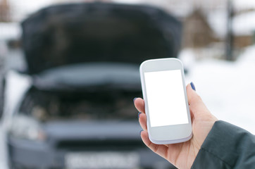 Evacuation call concept.Mobile phone with blank screen on on broken car background. Call to a car mechanic.