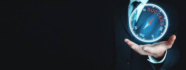 Businessman holding compass with the word success.