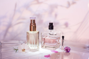 Different perfume bottles and sampler with plants on a pink floral background. Selective focus. Perfumery collection, - obrazy, fototapety, plakaty