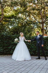 Fototapeta premium Bride and groom walk through the park in the city of Ravenna.