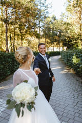 Bride and groom walk through the park in the city of Ravenna.
