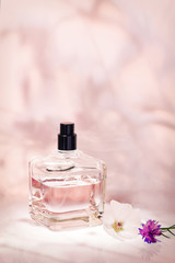 Perfume bottle with plants on a light pink floral background. Selective focus. Perfumery...