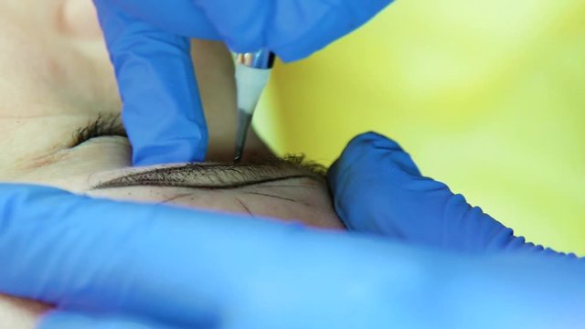 Beautician doing eyebrow microblading closeup. Beauty procedure