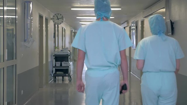 People in a clinic building. Man and woman walking through an empty hallway in hospital.