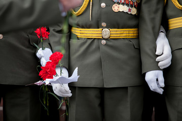 Carnation flowers in a hand of unidentified veteran. Selective focus.