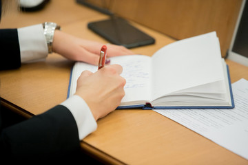 Businesswoman makes a note in notebook.