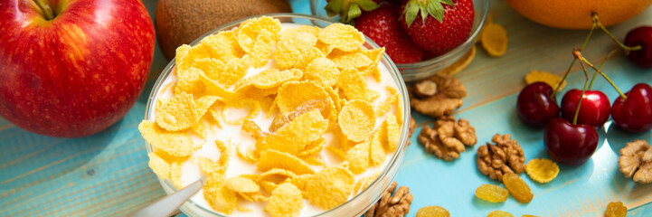 Tasty cornflakes with milk and fruits in glass bowl