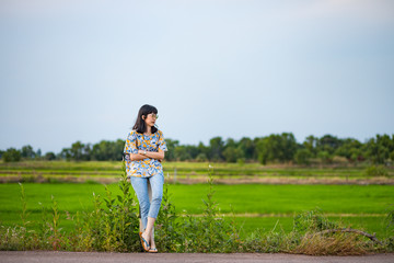 Beautiful young Asian woman on the road with rice field in the background