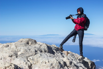 Photographer takes picture while standing on the mountain peak at strong wind