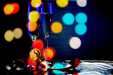 Christmas composition with a glass of sparkling wine, Christmas decorations and cork, on a dark background with blurred lights of the city.