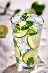Caipirinha, Mojito cocktail, vodka or soda drink with lime, mint and straw on sand background