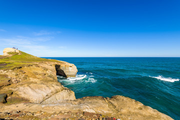 Sculpted cliffs, eroded rock formations and rough sea waves at Tunnel Beach, Otago region, South Island, New Zealand
