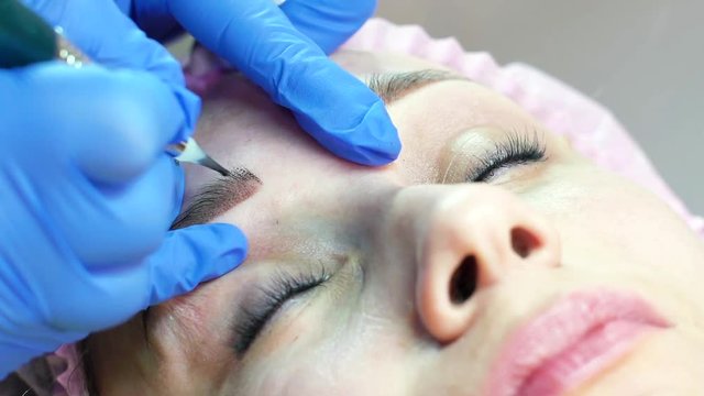 closeup of young woman face getting eyebrow microblading in beauty salon. Beauty procedure, permanent tattoo