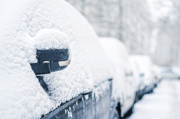Cars in the parking lot are covered with a thick layer of snow. Concept: winter weather and car...