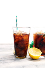 Softdrink with ice cubes, lemon and straw in glass