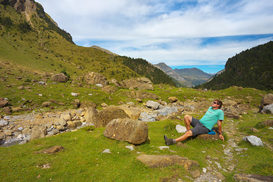 Resting tourist on the stony meadow in the mountain valley nearby resort of Gavarnie, Pyrenees