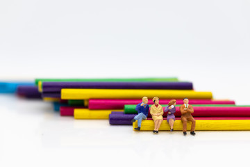 Miniature people: Businessmen sitting on colorful wood sticks. Image use for a variety of ideas, business team concept.