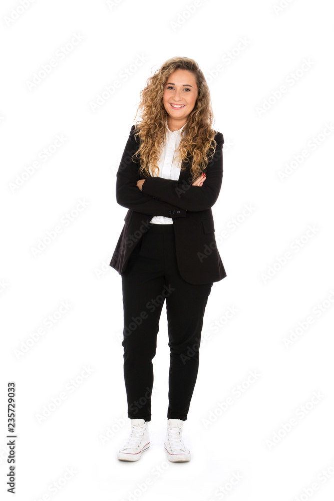 Wall mural Smiling girl with curly blonde hair, she is standing with her arms crossed, wearing a black suit and white shirt and sneakers