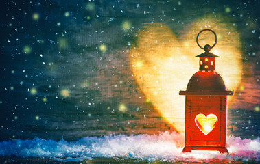 Red lantern with a heart cut out lit by a glowing candle