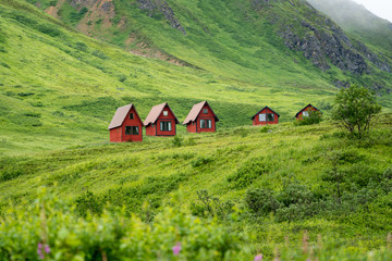 Abandoned red cabins sit in the green lush mountains of Alaska’s Hatcher Pass near Independence...