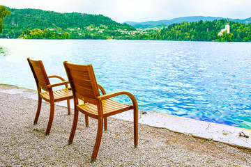 Two chairs on the shore of the resort lake. View of the mountains and the forest.