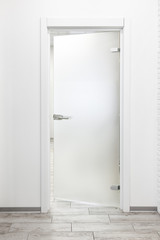 Minimalist white office interior with frosted glass door ajar