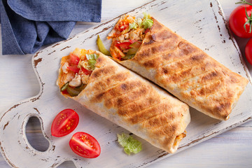 Chicken wraps with tomatoes, pickles, cabbage lettuce and onion. Tortilla, burritos, sandwiches, twisted rolls. overhead, horizontal