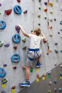 Artificial climbing facility and Caucasian boy with safety line on wall