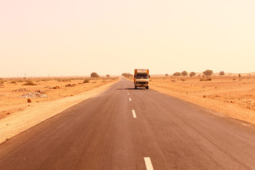 A truck moving on a road through a desert