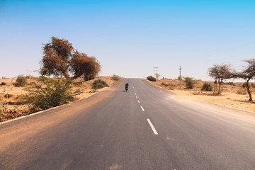 A motorcycle rider traveling solo through a desert