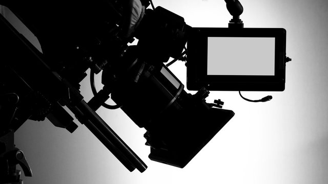 Silhouette images of video camera in tv commercial studio production which operating or shooting by cameraman and film crew team in set and prop on professional crane and tripod for pan tilt or shift