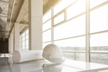 white helmet, blueprints of a building on a construction site on a window background