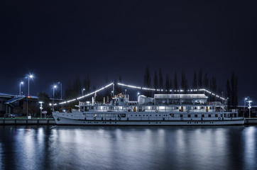 Fototapeta na wymiar NIGHT CITY - An old stylish cruise ship by the river bank in Szczecin 