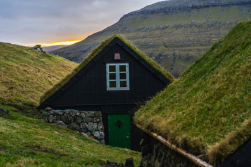 Fototapeta na wymiar Scenic landscape view of traditional historic stone wooden house/building with grass (turf) roof in Gasadálur village, Vágar Island. Tourist popular attraction/place in Faroe Islands (Denmark)