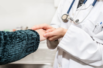 Doctor holding patient's hands, helping and empathy concept.