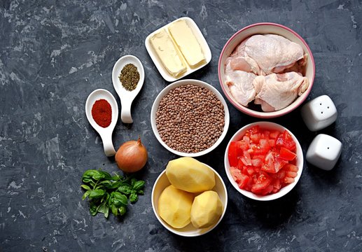 Ingredients for the preparation of chicken stew with lentils, potatoes and tomatoes: Chicken pieces, lentils, tomatoes, butter, peeled potatoes, onions, fresh basil, spices, salt, pepper. Top view.