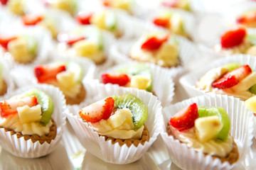 Close up of small sweet canapes arranged on a mirror plate over light background - selective focus
