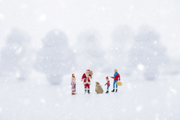 Miniature people in Christmas Theme. Santa Claus giving Christmas gift to children on Christmas day