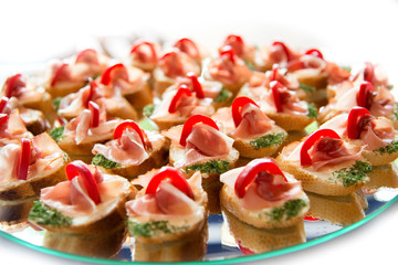 Close up of small canapes arranged on a plate over light background - selective focus