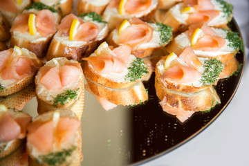 Close up of small canapes arranged on a plate over light background - selective focus